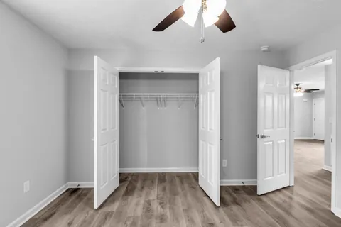 an empty room with wooden floor a ceiling fan and windows