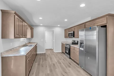 a kitchen with stainless steel appliances granite countertop a refrigerator a stove and a sink