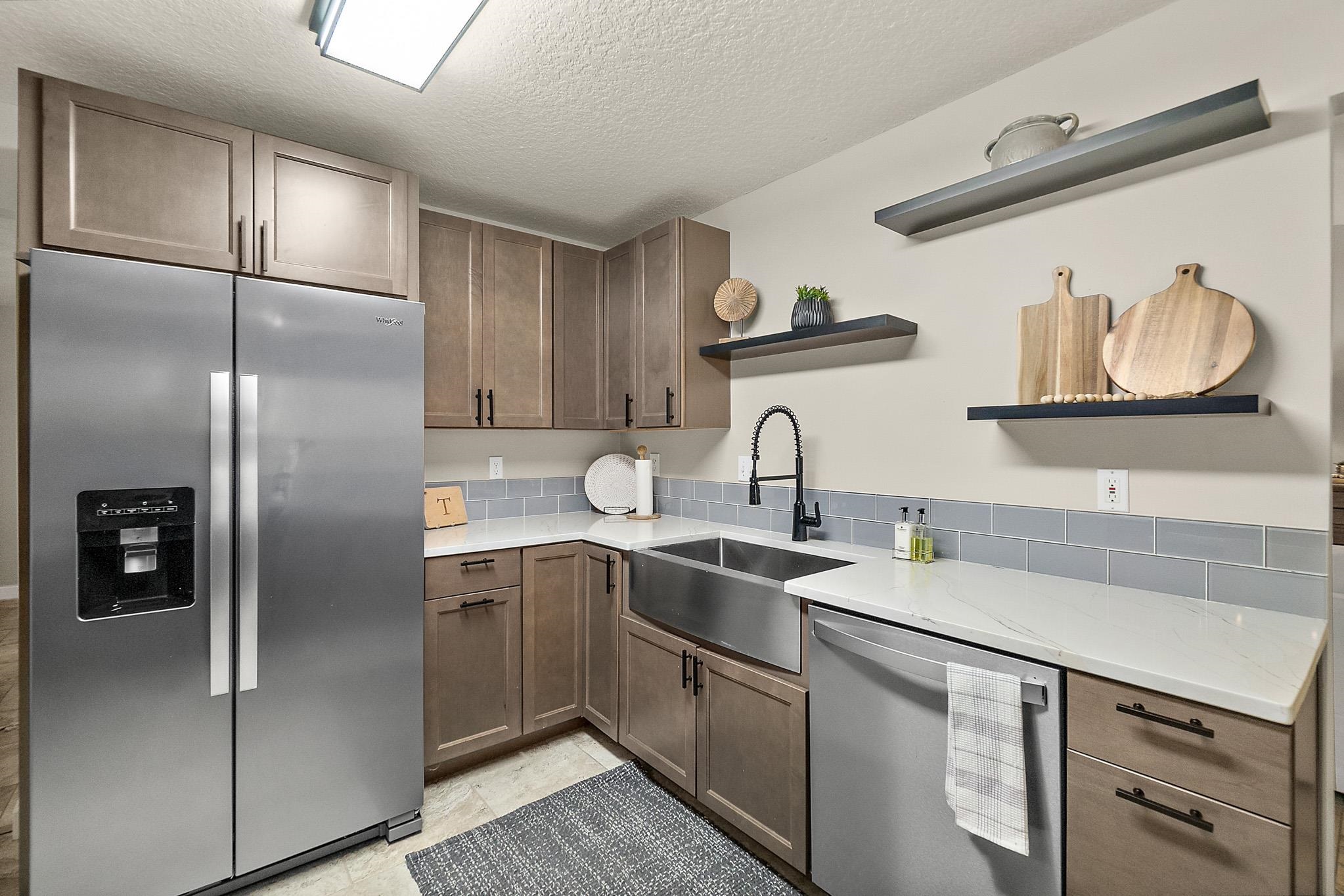 3253 Turtle Creek Road St. Augustine, FL 32086 - Photo 11 of 40 Kitchen with stainless steel appliances, open shelves, light stone countertops, and a textured ceiling