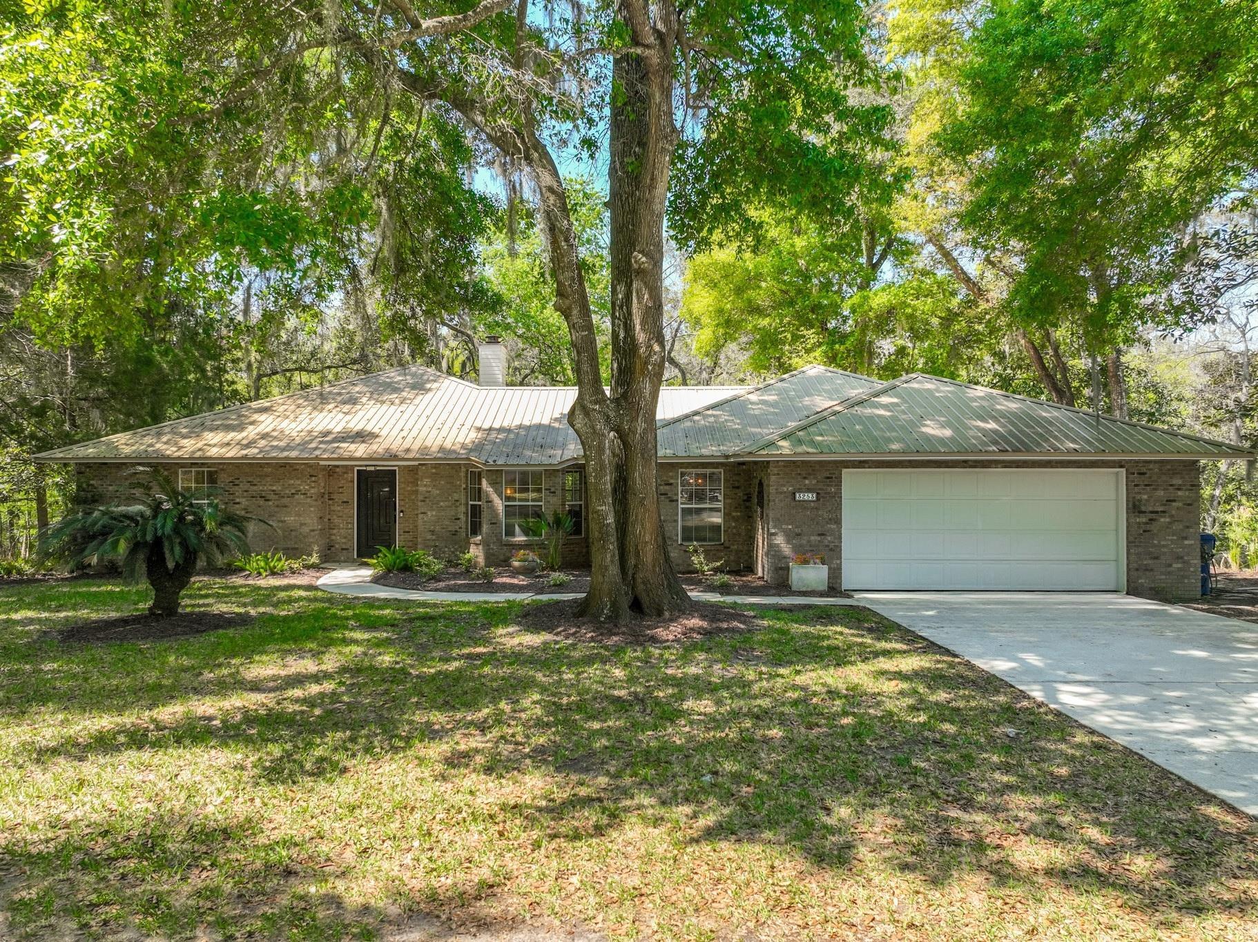 3253 Turtle Creek Road St. Augustine, FL 32086 - Photo 2 of 40 Ranch-style house featuring a garage, a metal roof, a front yard, concrete driveway, and brick siding