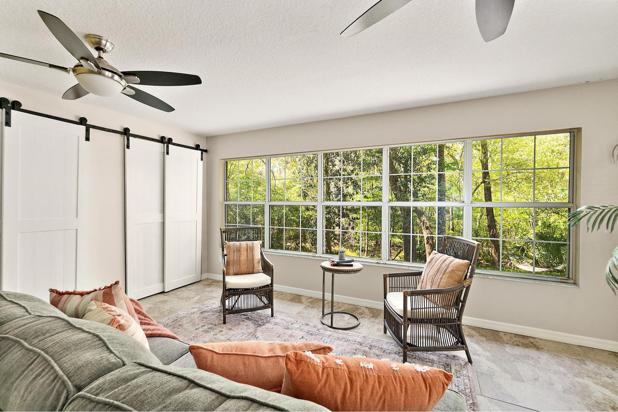 3253 Turtle Creek Road St. Augustine, FL 32086 - Photo 30 of 40 Living room featuring ceiling fan, a barn door, a textured ceiling, and light stone finish floors
