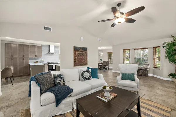 a living room with furniture kitchen view and a chandelier