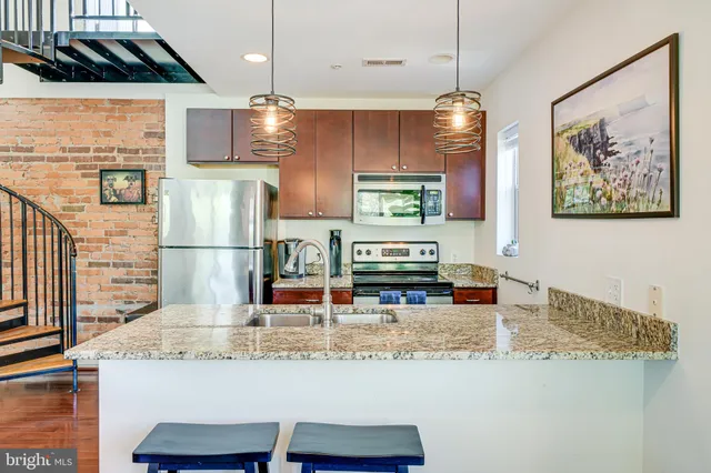 a kitchen with granite countertop kitchen island stainless steel appliances a refrigerator sink and stove