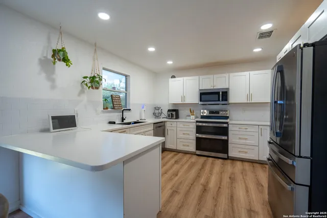 a kitchen with a refrigerator a stove top oven a sink and cabinets