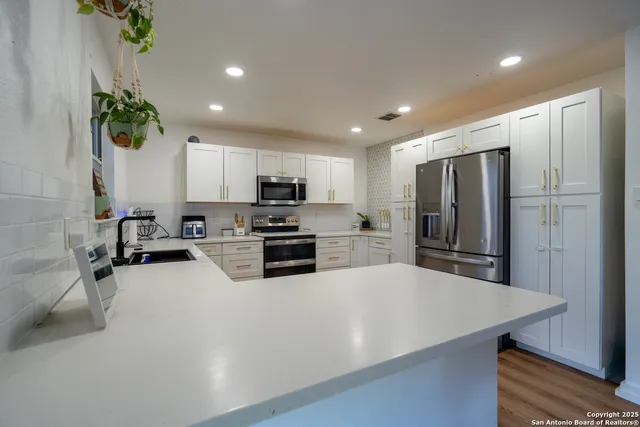 a kitchen with granite countertop a refrigerator a sink a stove a microwave a counter top space and cabinets