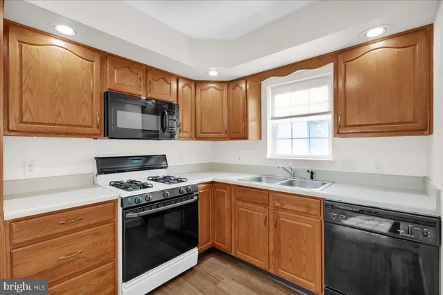a kitchen with stainless steel appliances granite countertop a sink a stove a microwave and wooden cabinets