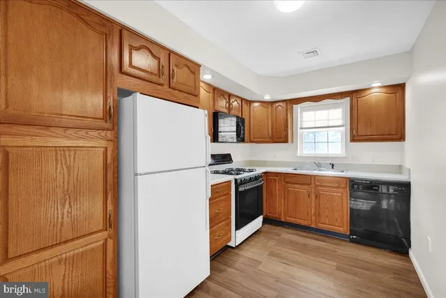 a kitchen with stainless steel appliances granite countertop a refrigerator stove a sink and dishwasher with wooden floor