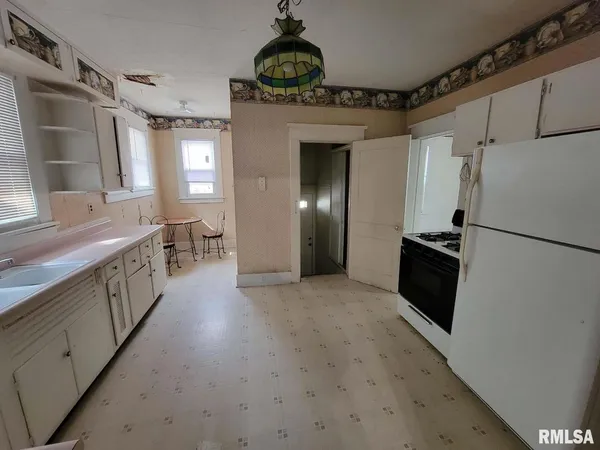 a hallway with wooden floor windows and a kitchen