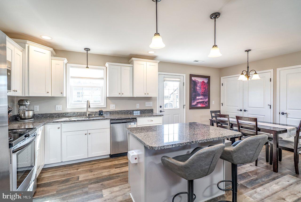 107 8th Street Grottoes, VA 24441 - Photo 11 of 45 a kitchen with stainless steel appliances granite countertop a stove top oven a sink a dining table and chairs with wooden floor