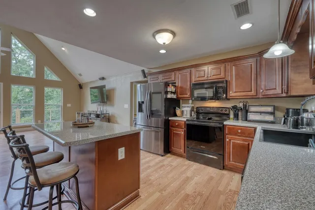a kitchen with stainless steel appliances granite countertop sink stove refrigerator and cabinets