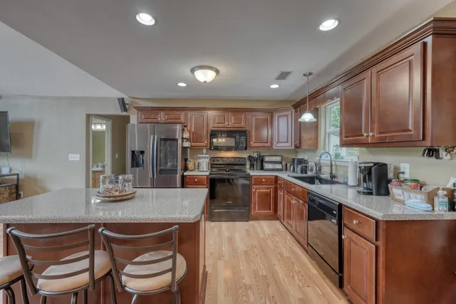 a kitchen with stainless steel appliances granite countertop a stove top oven a sink dishwasher a dining table and chairs with wooden floor