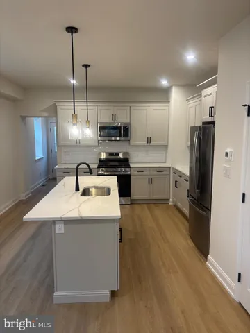 a kitchen with stainless steel appliances granite countertop a sink a stove a refrigerator and island with wooden floor