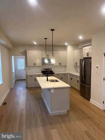 a kitchen with stainless steel appliances granite countertop a refrigerator a sink dishwasher a stove and a wooden floors