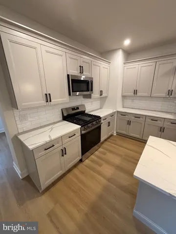 a kitchen with stainless steel appliances white cabinets and wooden floors
