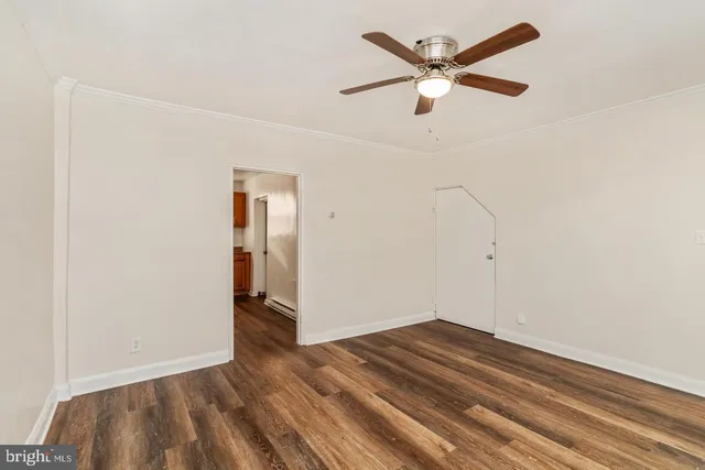 an empty room with wooden floor and ceiling fan