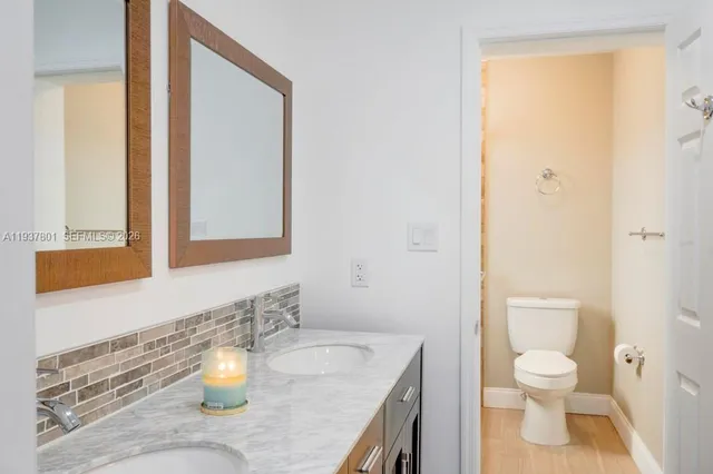 a bathroom with a granite countertop sink toilet and a mirror
