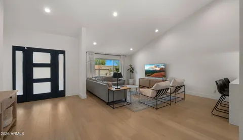 a living room with furniture and a flat screen tv with kitchen view