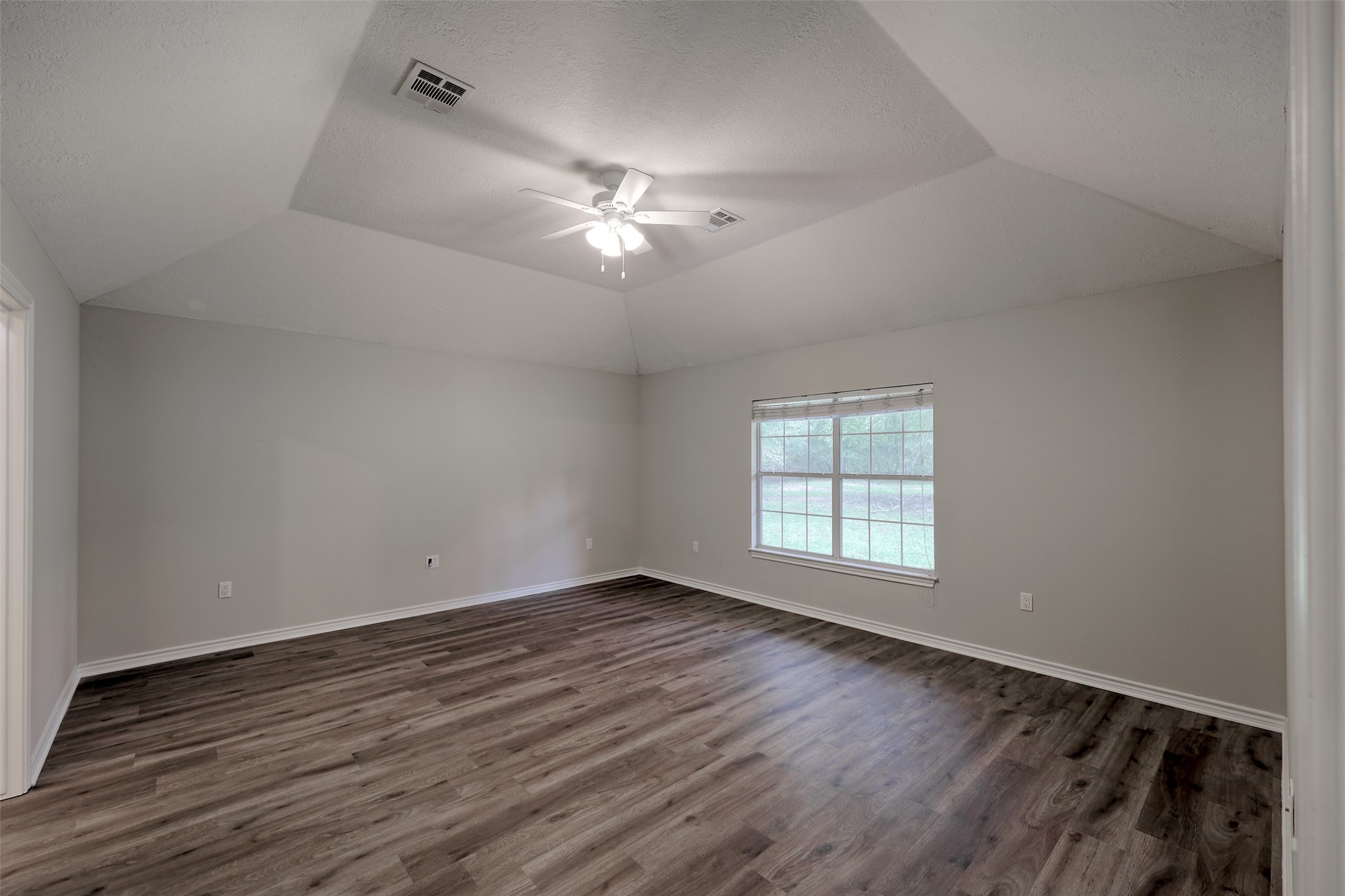3131 Sapp Road Conroe, TX 77304 - Photo 18 of 48 an empty room with wooden floor ceiling fan and windows