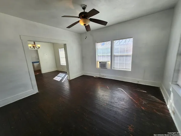 a view of an empty room with wooden floor and a window