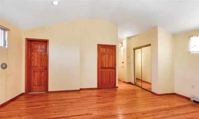 a view of an empty room with wooden floor and closet