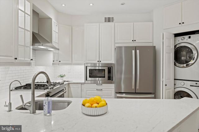 a kitchen with stainless steel appliances a sink a stove a refrigerator cabinets and a counter space