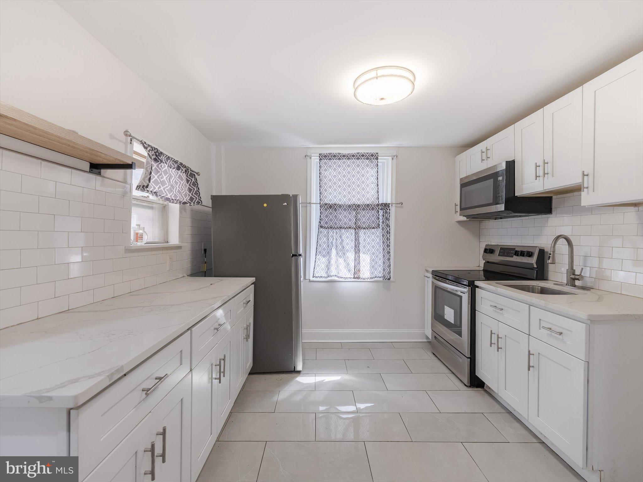 5428 Belmar Street Philadelphia, PA 19143 - Photo 6 of 25 a kitchen with granite countertop a sink stove and cabinets