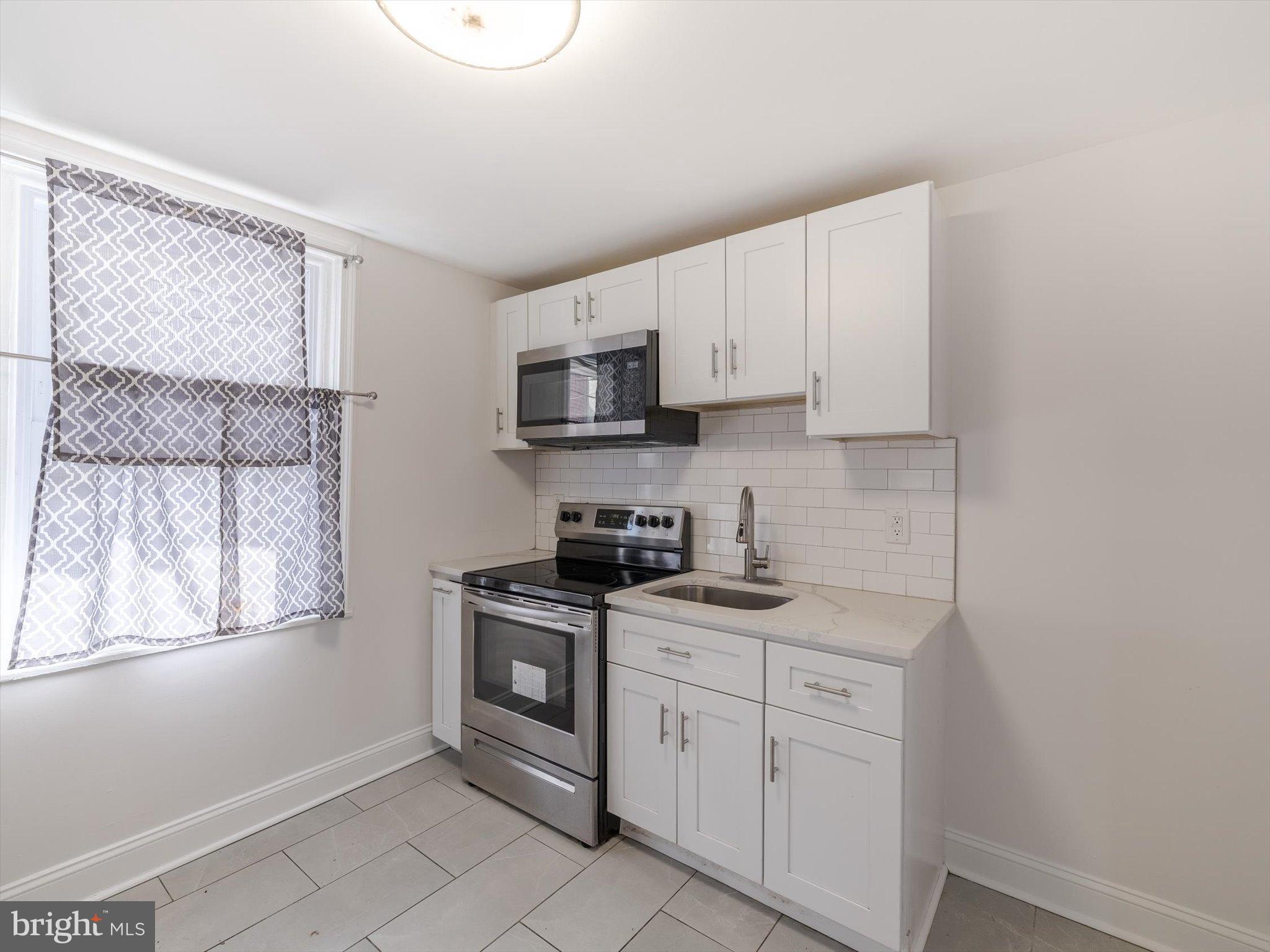 5428 Belmar Street Philadelphia, PA 19143 - Photo 8 of 25 a kitchen with white cabinets appliances and a window