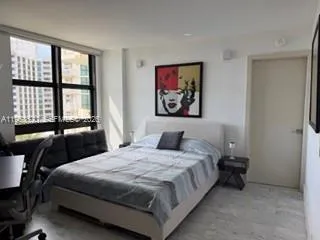 a bedroom with a bed a flat screen tv and balcony