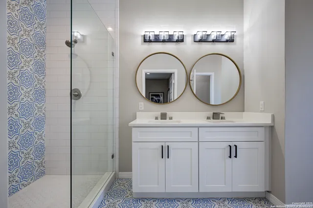 a bathroom with a double vanity sink mirror and shower