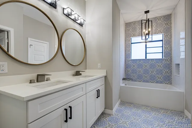 a bathroom with a double vanity sink mirror and bathtub