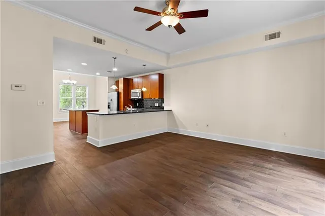 a living room with stainless steel appliances kitchen island hardwood floor and a ceiling fan