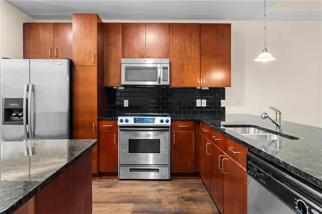 a kitchen with stainless steel appliances granite countertop a sink stove and refrigerator