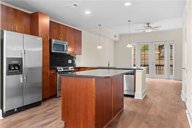 a kitchen with stainless steel appliances granite countertop a refrigerator a sink dishwasher and a large oven with wooden floor