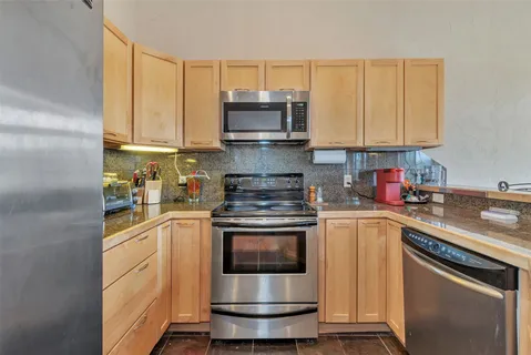 a kitchen with stainless steel appliances granite countertop a stove a sink and a refrigerator