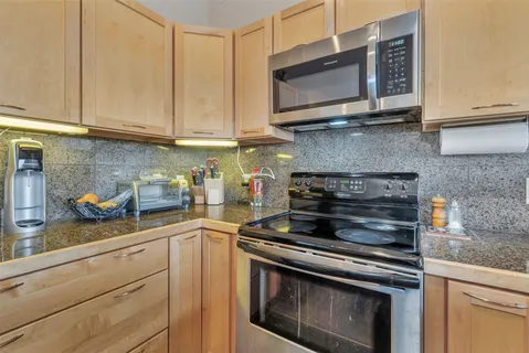 a kitchen with granite countertop white cabinets stainless steel appliances and a counter space