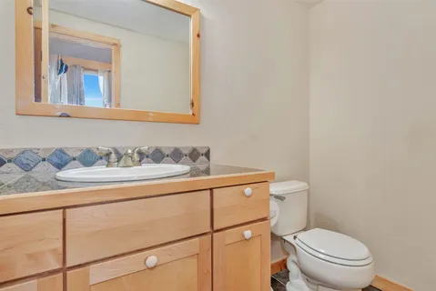 a bathroom with a granite countertop toilet sink and mirror