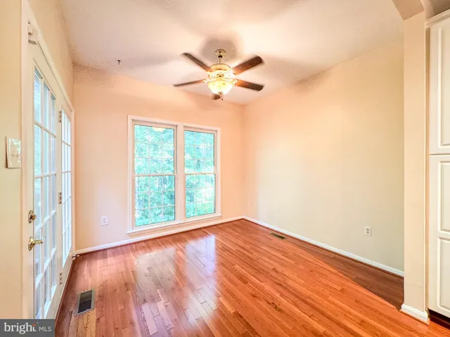 a view of an empty room with window and wooden floor