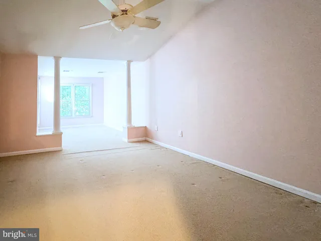 an empty room with a chandelier fan and windows