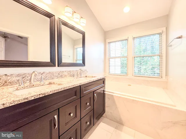 a bathroom with a granite countertop bathtub sink vanity and mirror