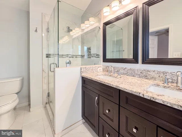 a bathroom with a granite countertop sink toilet and shower