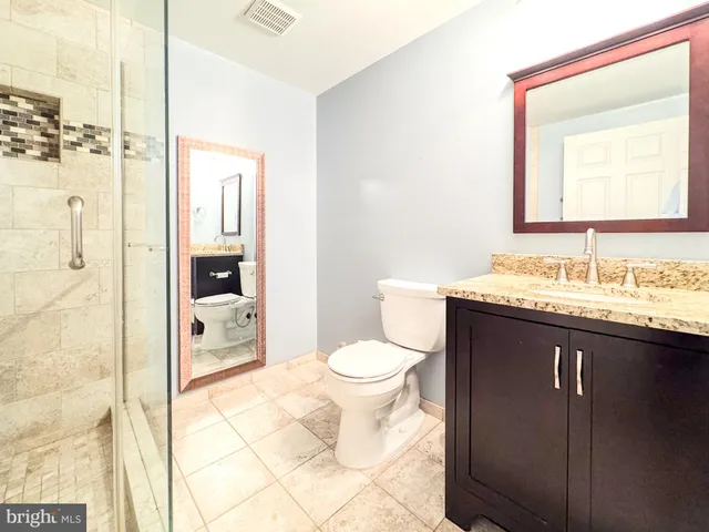 a bathroom with a granite countertop sink toilet and shower