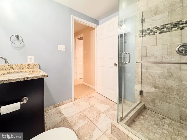 a bathroom with a granite countertop shower mirror and toilet