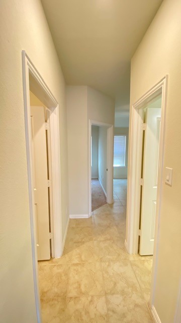 5002 Naples Grove Lane Rosharon, TX 77583 - Photo 9 of 38 Bright, inviting hallway with neutral tile flooring and multiple doorways leading to spacious rooms.