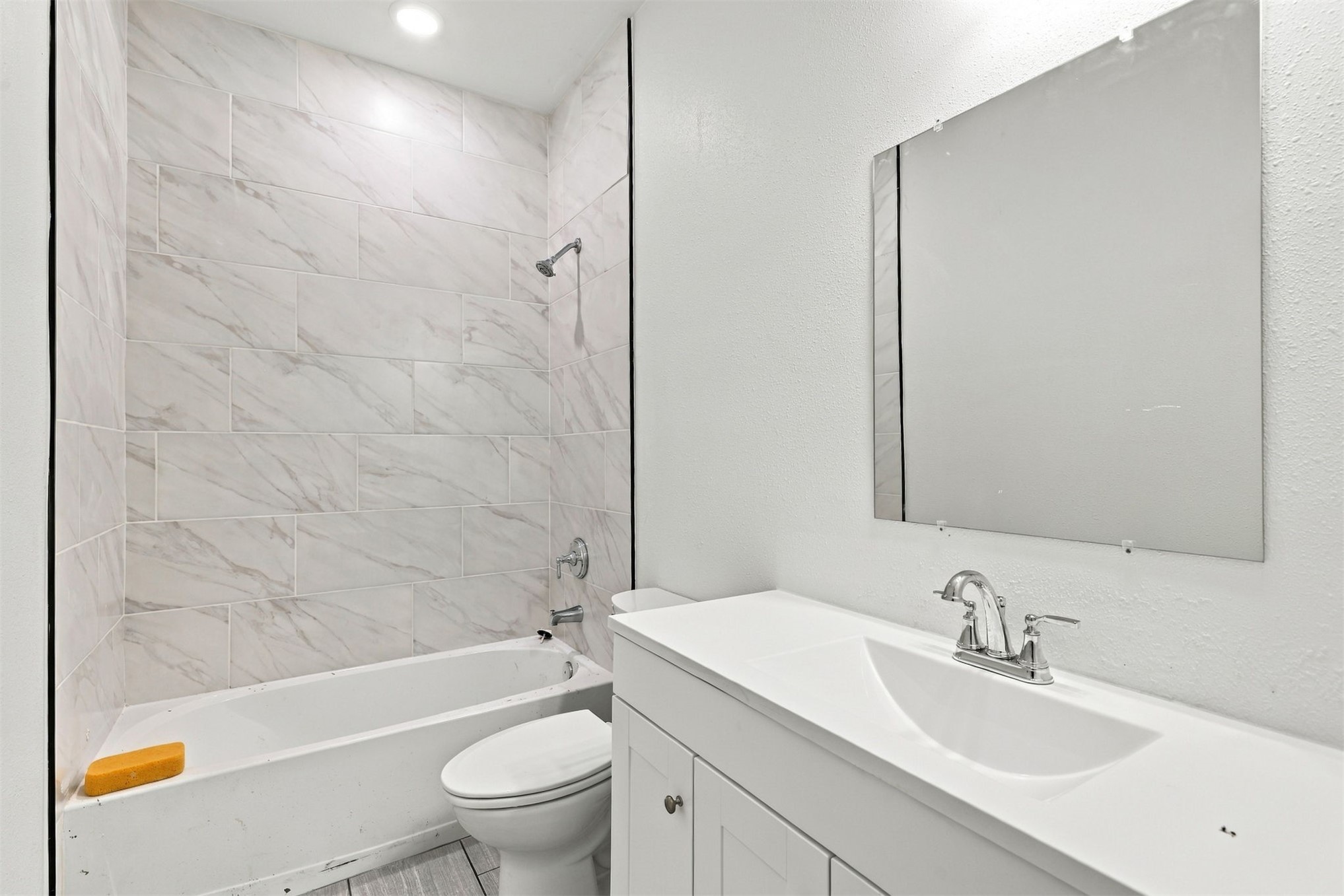 21 Redbird Lane Colbert, OK 74733 - Photo 8 of 27 Bathtub with large format wall tiling, white vanity with integrated sink, and wall-mounted mirror
