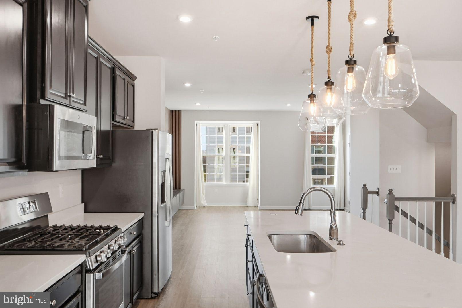 7917 Gladden Farm Way Hanover, MD 21076 - Photo 13 of 28 a kitchen with stainless steel appliances granite countertop a refrigerator a sink dishwasher a stove and a dining table with wooden floor