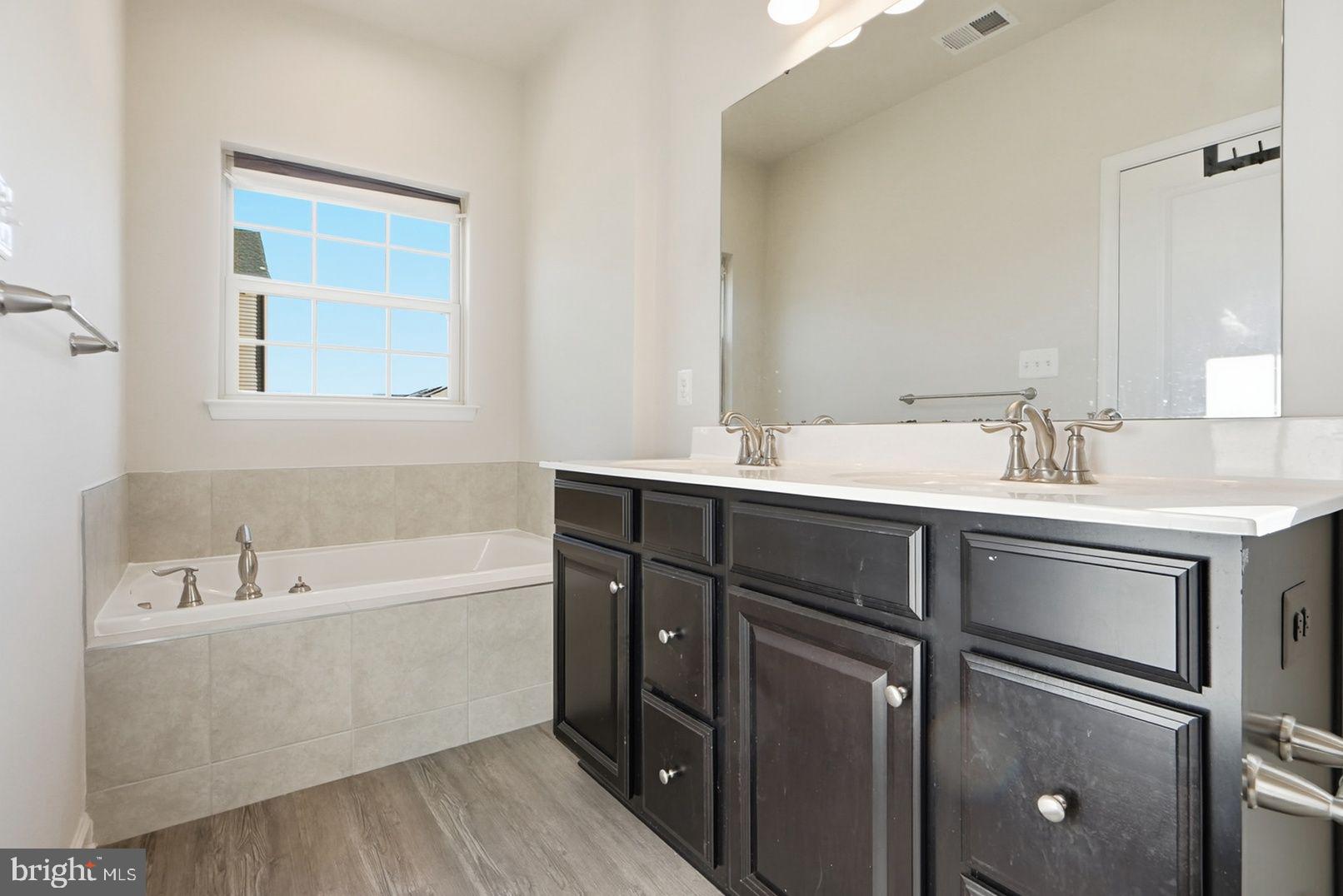 7917 Gladden Farm Way Hanover, MD 21076 - Photo 20 of 28 a bathroom with a tub sink double vanity and mirror