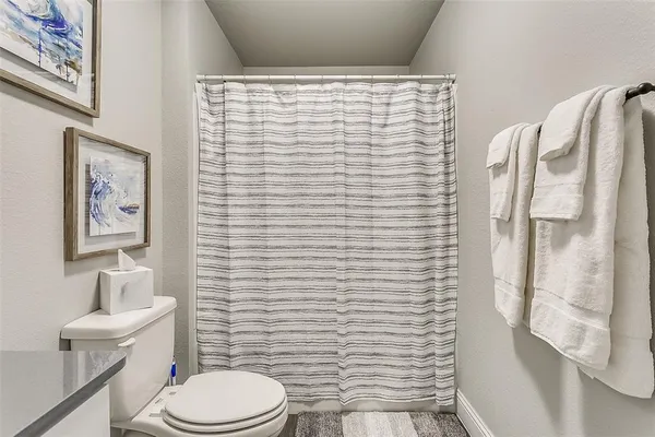 a bathroom with a toilet and a shower curtain