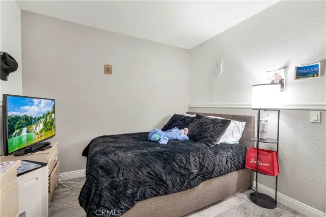 a bedroom with a bed and a lamp on dresser next to a window