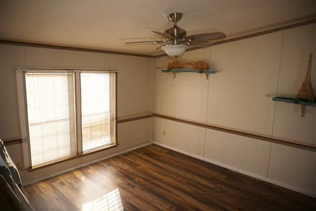 a view of empty room with wooden floor and fan