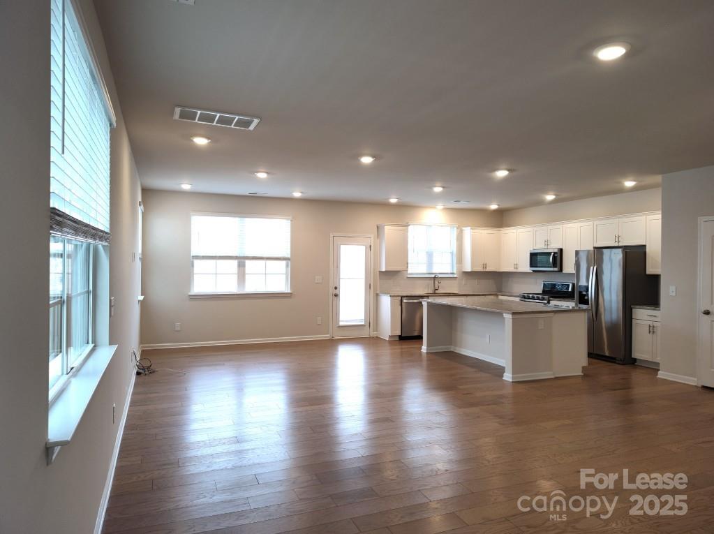 3327 Glenn Hope Way Matthews, NC 28104 - Photo 6 of 23 a view of kitchen with kitchen island granite countertop a stove top oven a sink and a potted plant with wooden floor